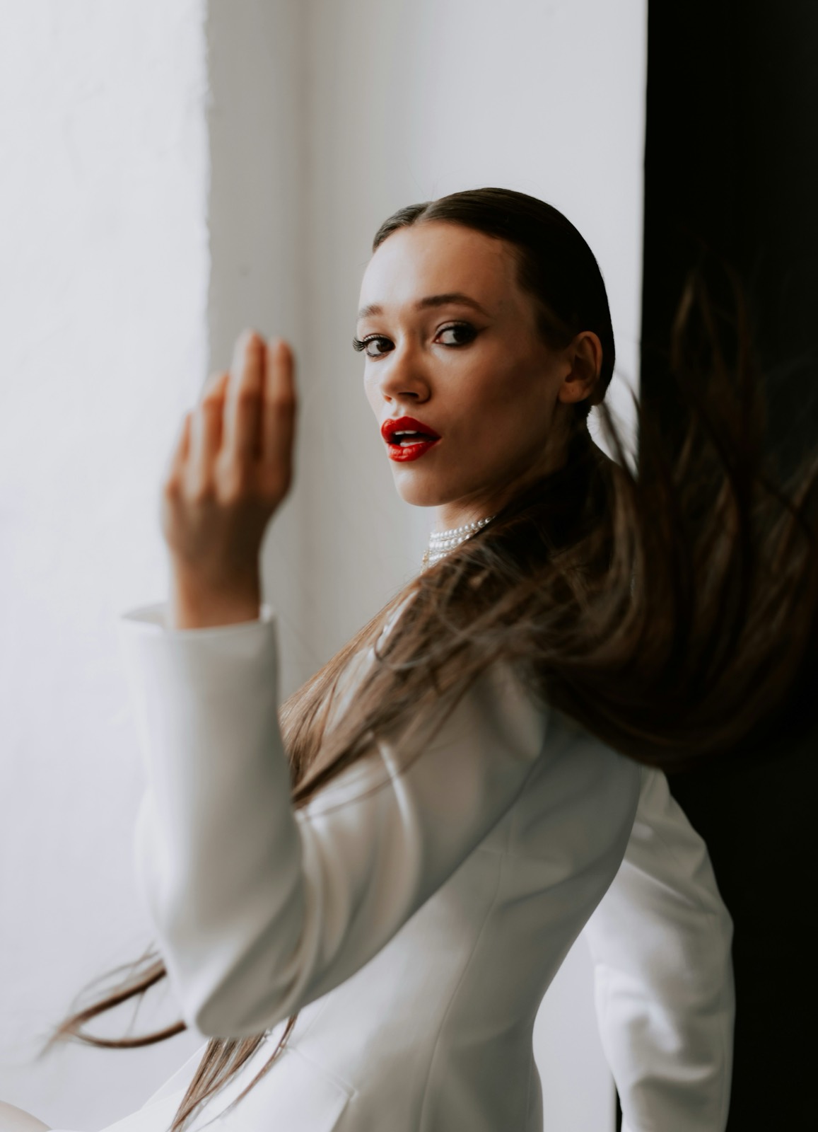 A woman in a white blazer looking over her shoulder