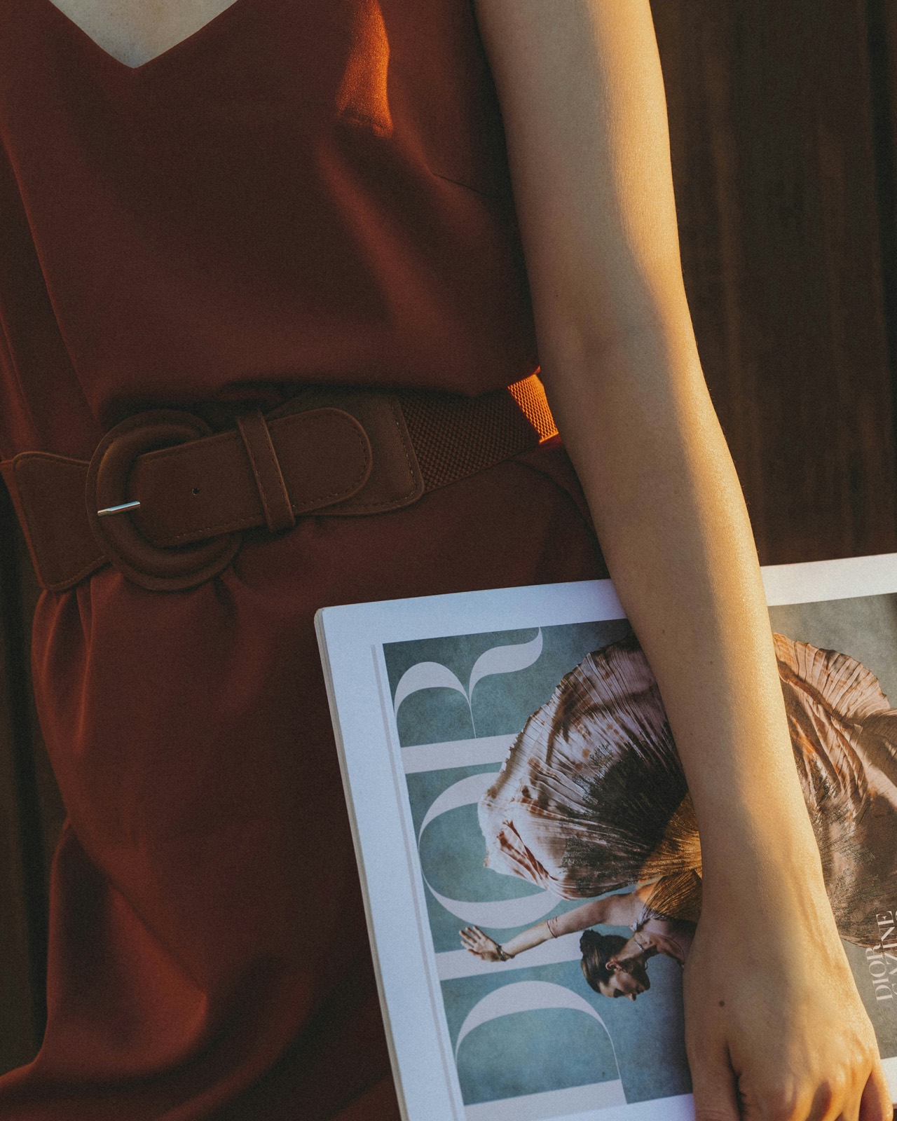 A woman in a burgundy dress holding a fashion magazine
